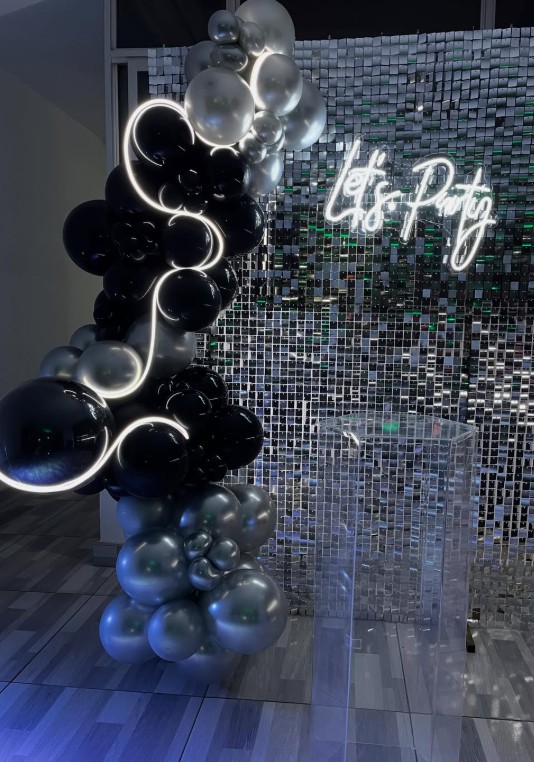 Salón con pared de espejos dorados y arco de globos en tono vino